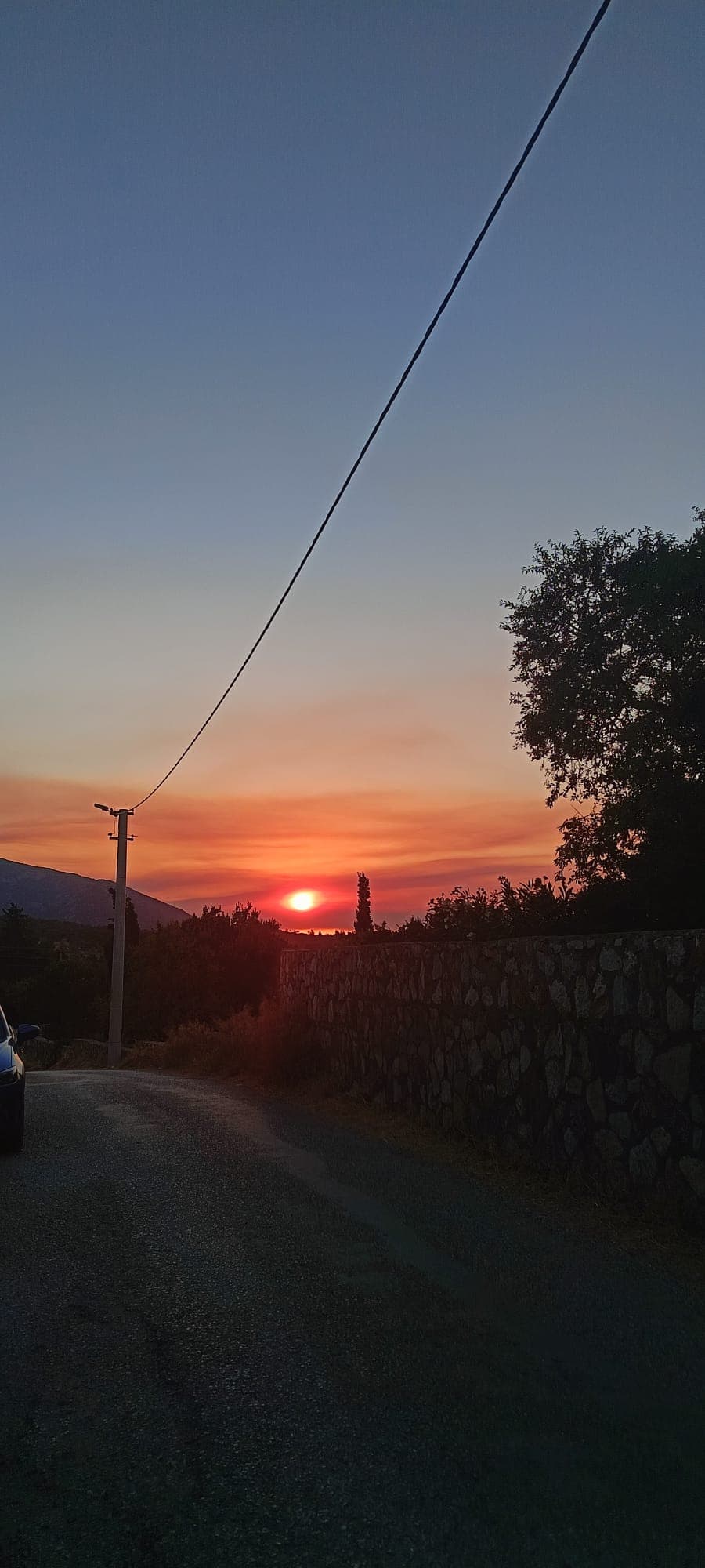 Datça'da taş duvarların ardından görünen turuncu gün batımı